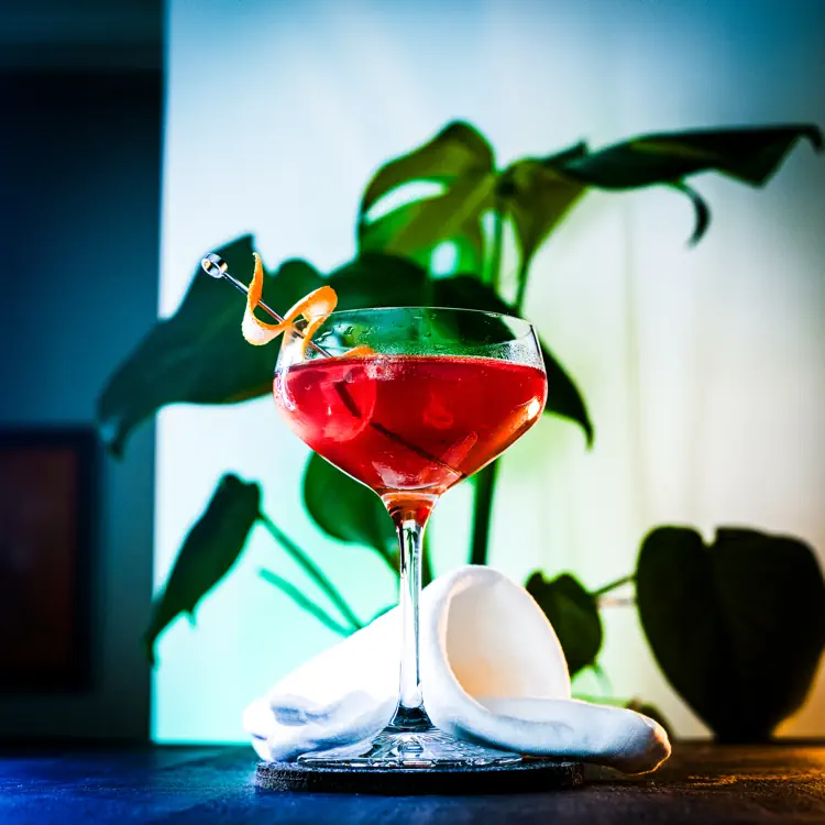 Red Tequila Sunrise in a stemmed glass with an orange-peel twist.